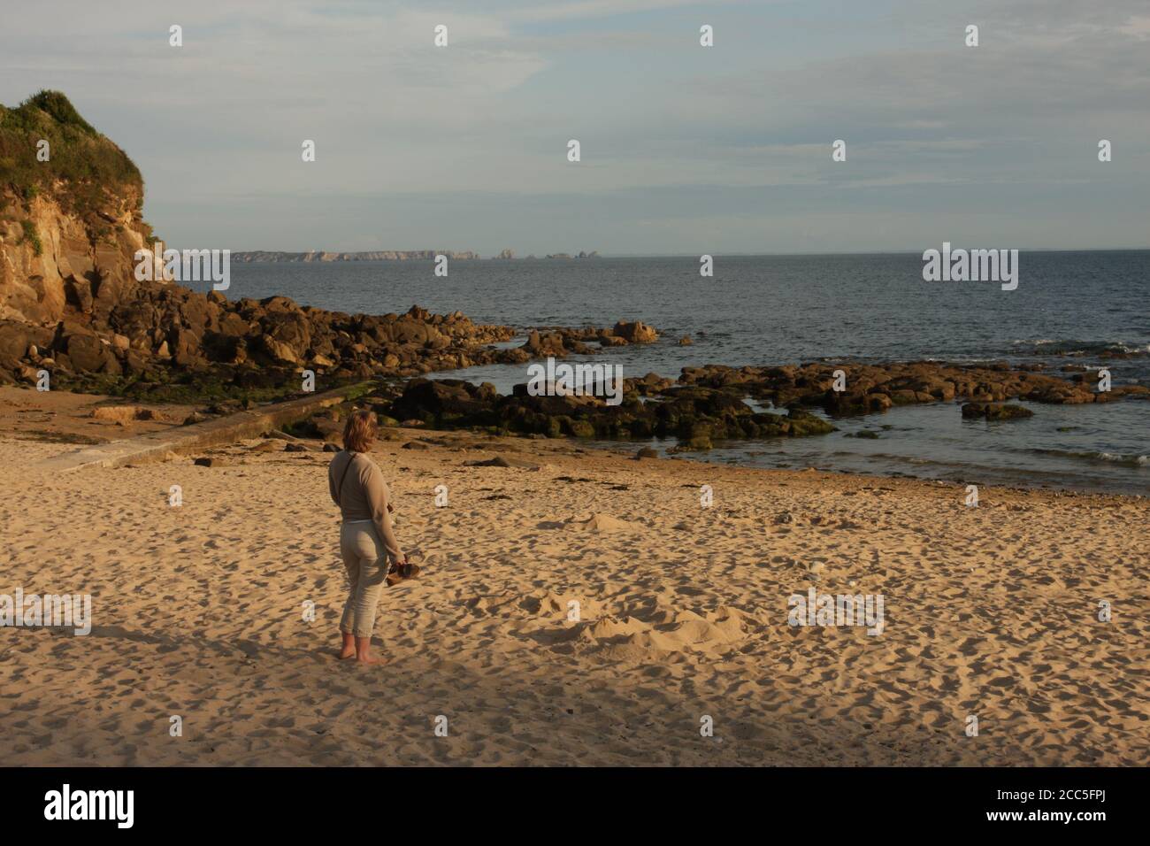 Una donna che guarda verso il mare mentre si trova su una spiaggia di sabbia, Brixham, Devon, Regno Unito Foto Stock