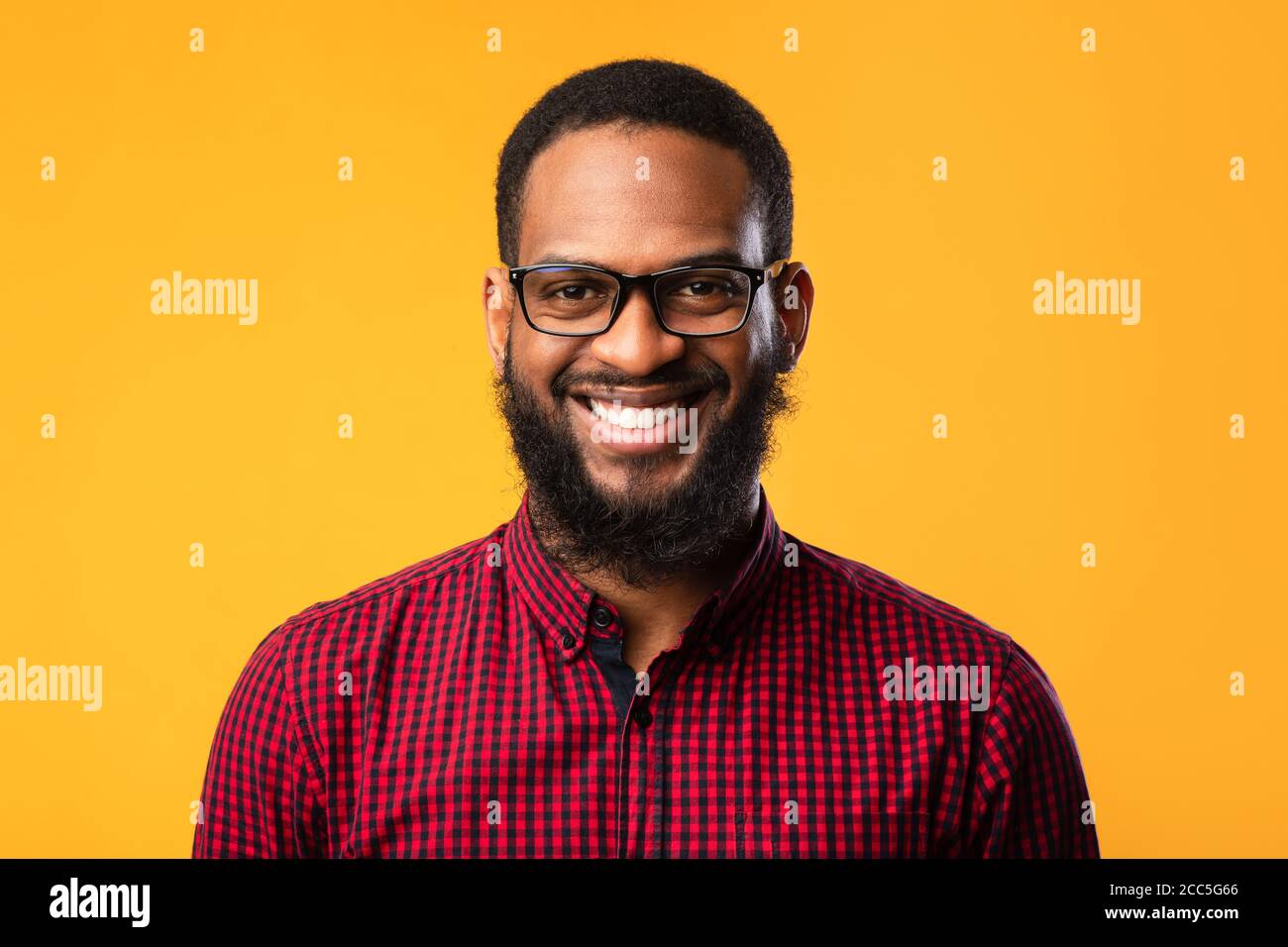 Sorridente afro uomo che posa su sfondo giallo Foto Stock