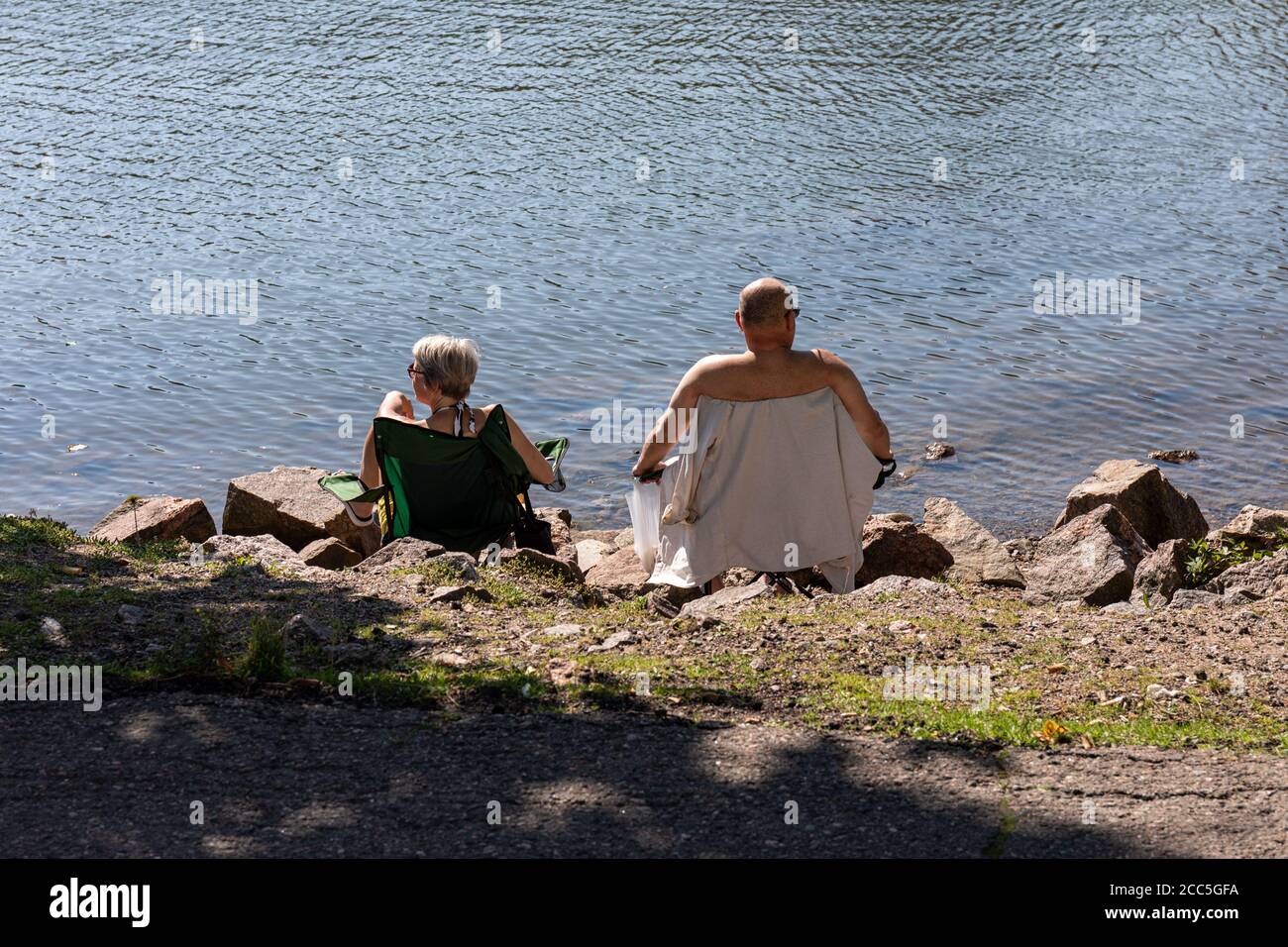 Coppia di mezza età seduta su sedie portatili da campeggio in acqua Foto Stock