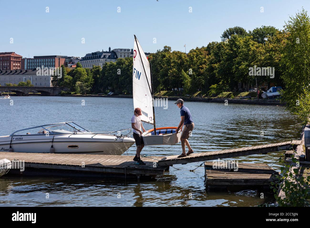 Uomini che trasportano uno skiff a vela nel distretto di Kaisaniemi di Helsinki, Finlandia Foto Stock