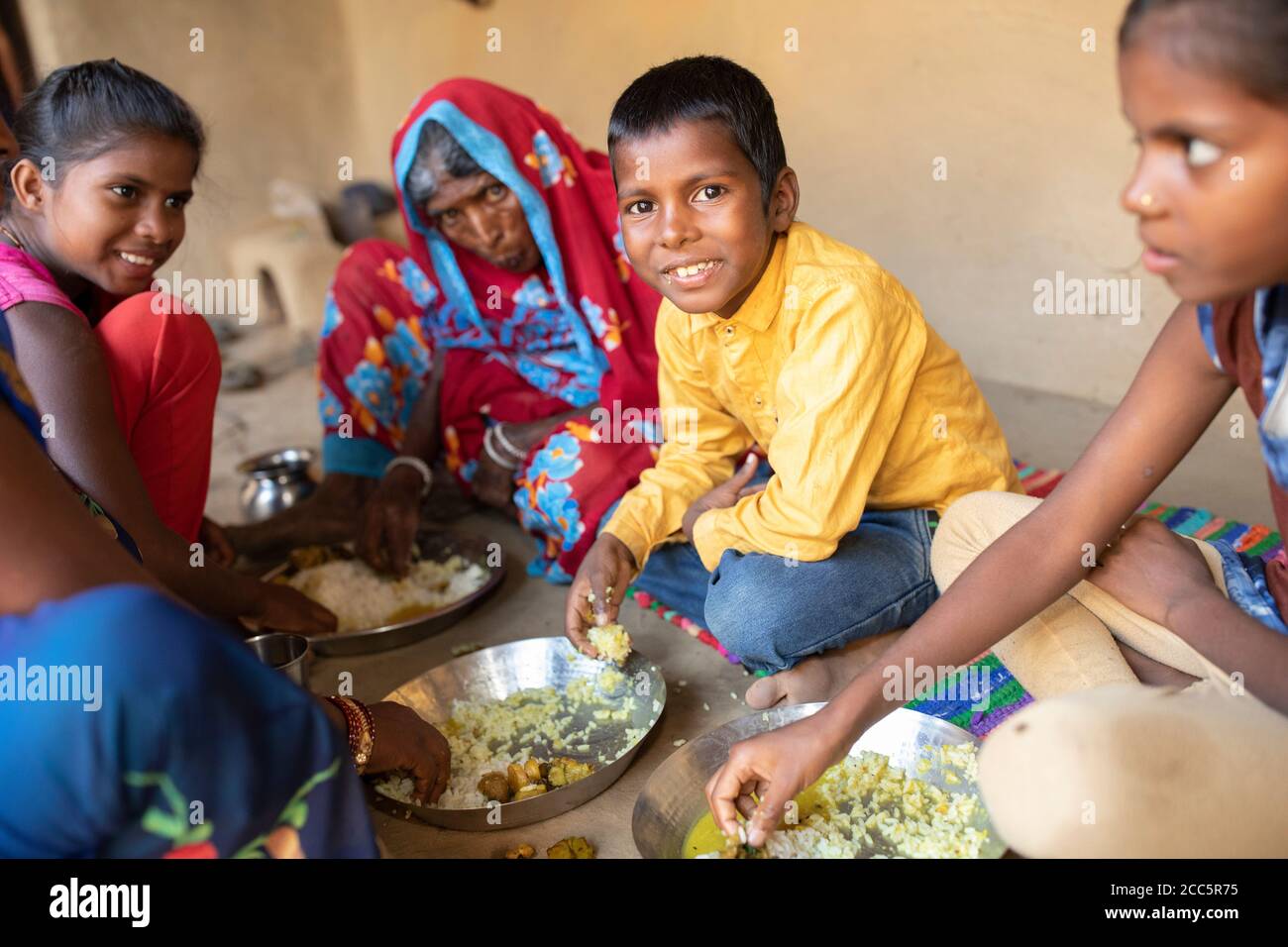 Una famiglia si siede insieme per un pasto tradizionale di verdure, riso e lenticchie nella loro casa a Bihar, India, Asia meridionale. Foto Stock