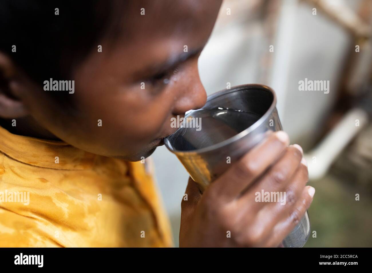 Un ragazzo di otto anni beve acqua dal nuovo rubinetto che sua madre aveva installato recentemente nella casa della famiglia a Bihar, India. Foto Stock