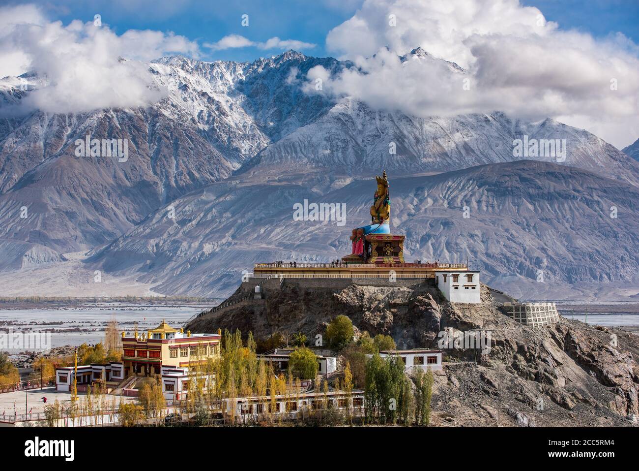 La statua del Buddha di Maitreya con le montagne di Himalaya sullo sfondo dal Monastero di Diskit o Diskit Gompa, la valle di Nubra, Leh Ladakh Foto Stock