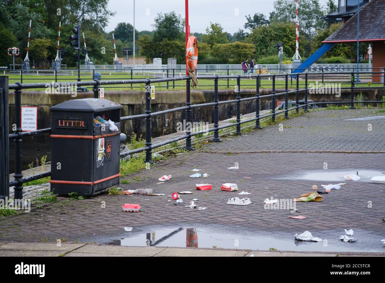 Spazzatura e lettiera che circondano un cestino di rifiuti a Preston Docks nel Lancashire. Foto Stock