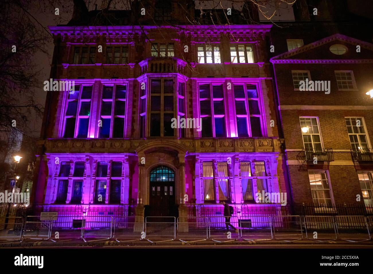 La sede della Royal Institution of Chartered Surveyors (RICS) sul Parlamento Piazza di Londra di notte illuminata da luci viola Foto Stock