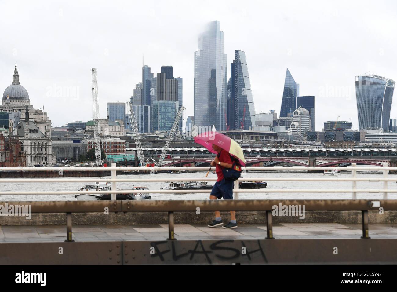 Un uomo cammina lungo Southbank a Londra, poiché molte parti del Regno Unito sperimentano il tempo umido prima dell'arrivo di Storm Ellen, che si prevede porterà venti forti. Foto Stock