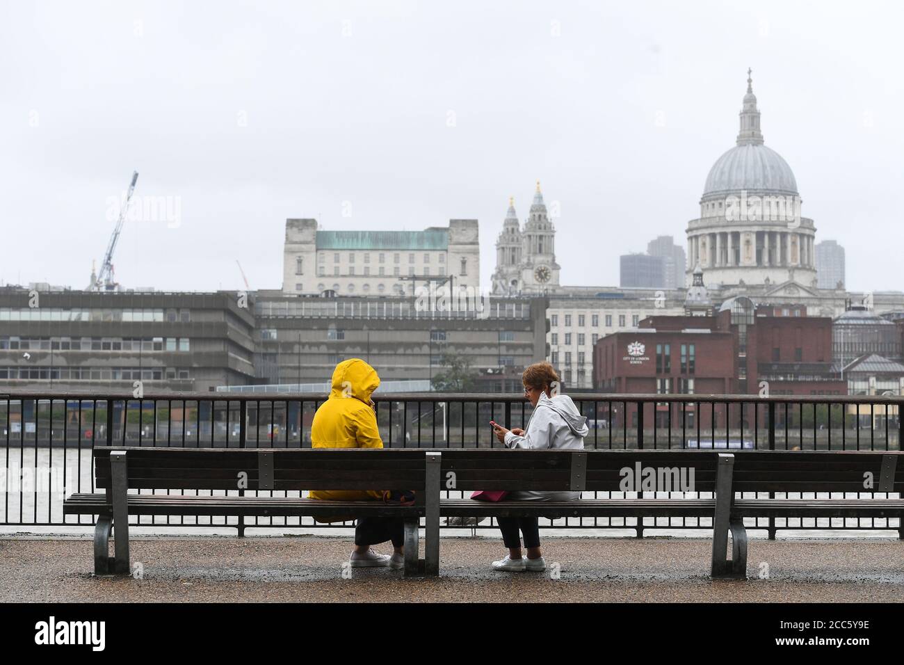 La gente si siede su una panchina su Southbank a Londra, poiché molte parti del Regno Unito sperimentano il tempo umido prima dell'arrivo di Storm Ellen, che si prevede porterà venti forti. Foto Stock