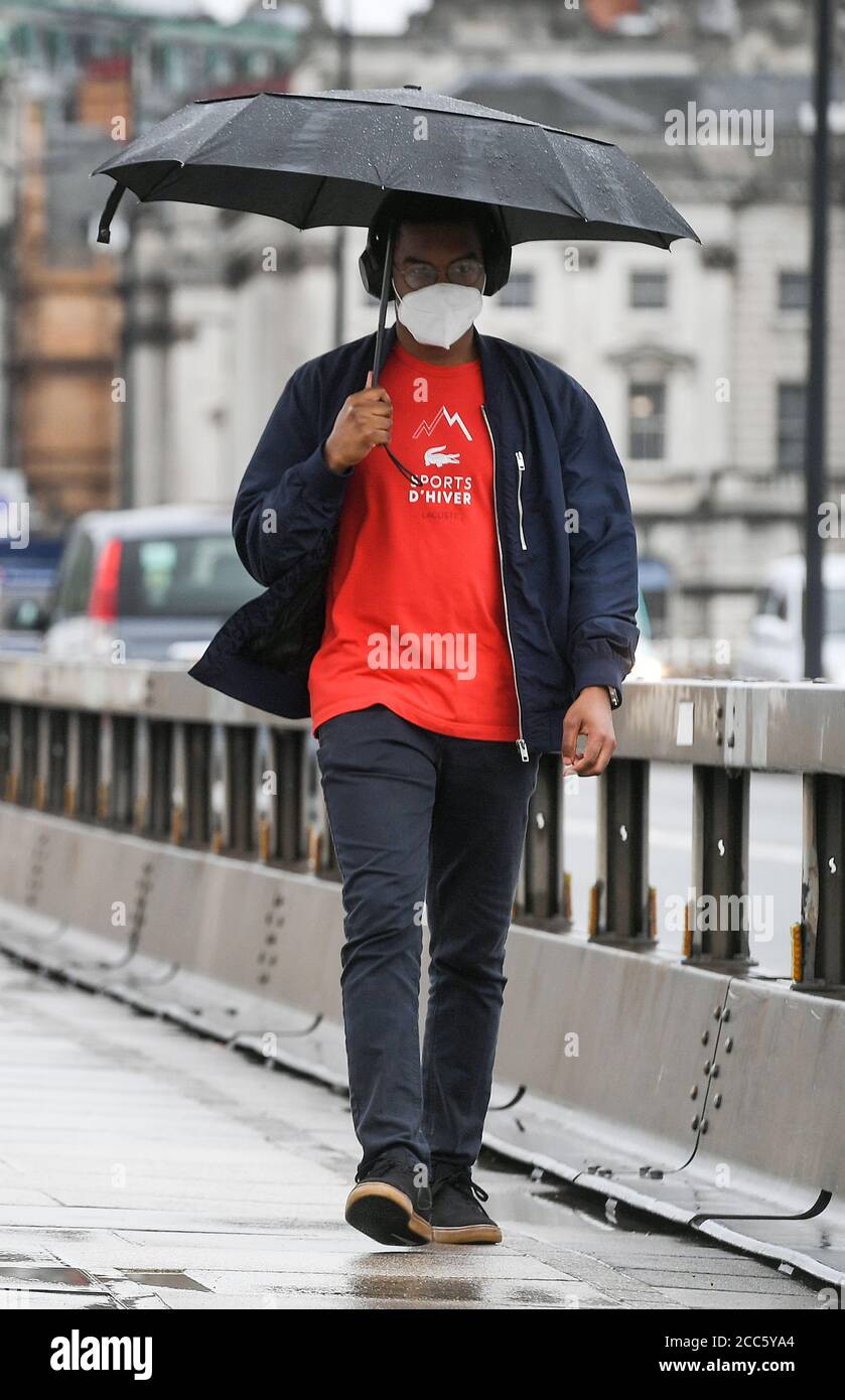 Un uomo attraversa il ponte di Waterloo a Londra, poiché molte parti del Regno Unito sperimentano il tempo umido prima dell'arrivo di Storm Ellen, che si prevede porterà forti venti. Foto Stock