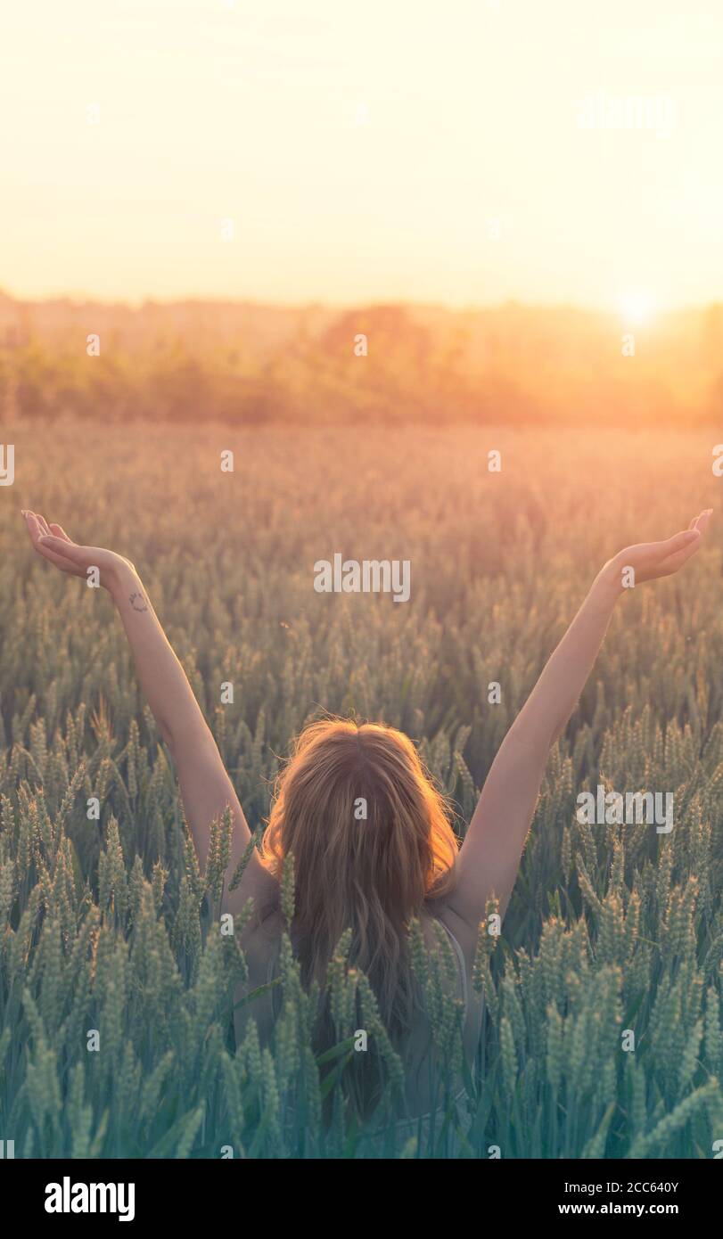 pace e amore, la donna hipster celebra la nascita del sole in un campo di grano Foto Stock