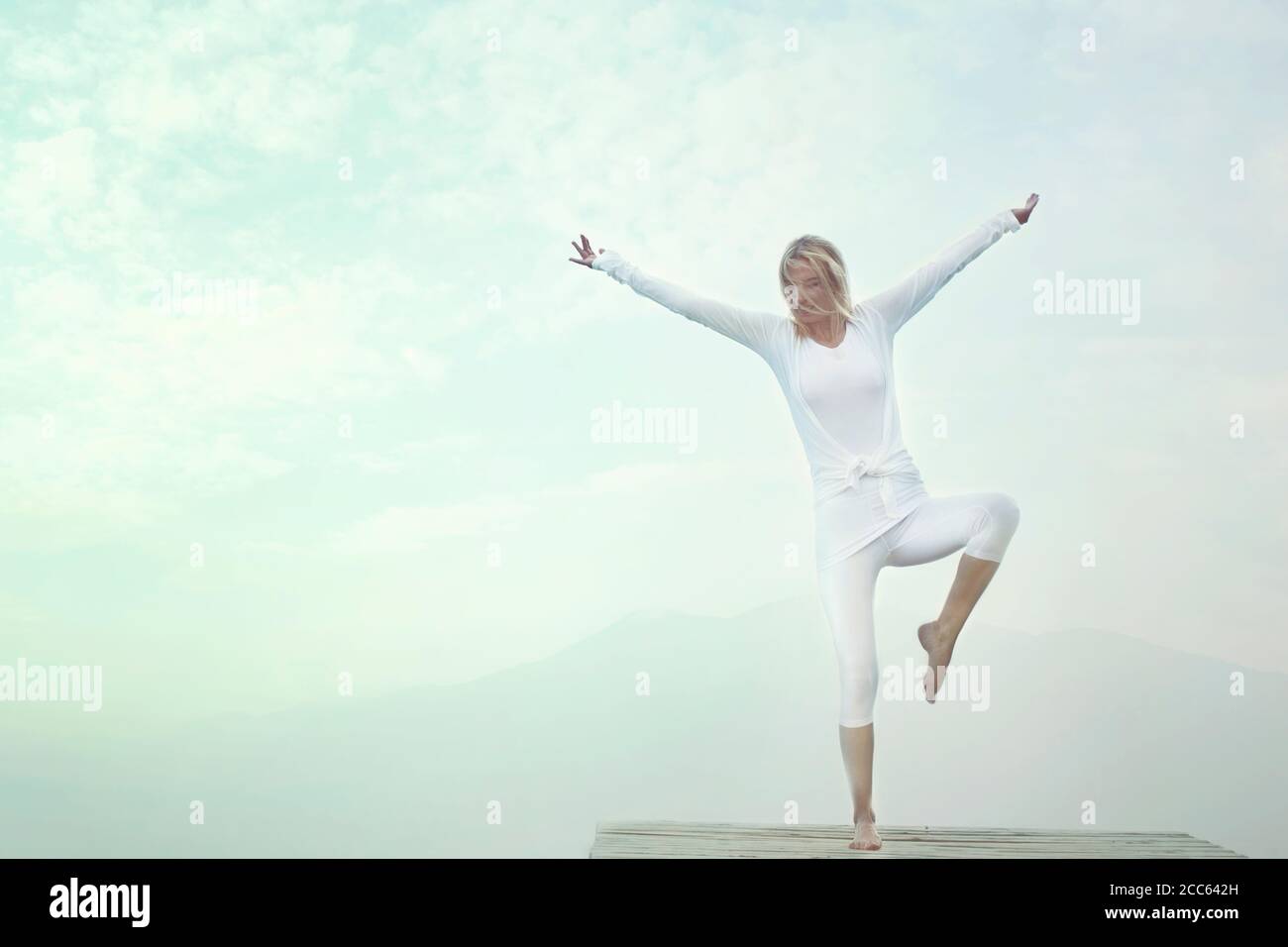 donna che fa esercizi di yoga di fronte ad un cielo blu Foto Stock