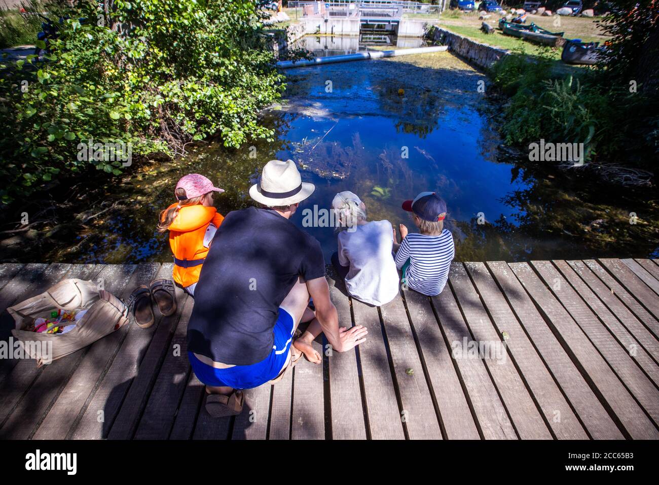 06 agosto 2020, Meclemburgo-Pomerania occidentale, Fleeter Mühle: I bambini guardano il pesce in acqua su un molo di legno sulla Vilzsee vicino al Fleether Mühle. Migliaia di vacanzieri stanno attualmente viaggiando in barca, in bicicletta o a piedi nel distretto dei laghi di Mecklenburg. Foto: Jens Büttner/dpa-Zentralbild/ZB Foto Stock