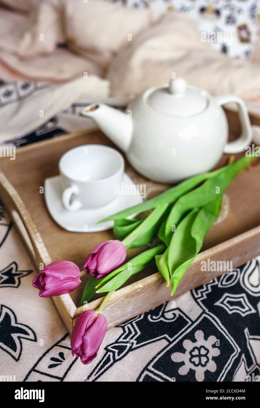 Tulipani con teiera e tazza sono su vassoio in camera da letto Foto Stock
