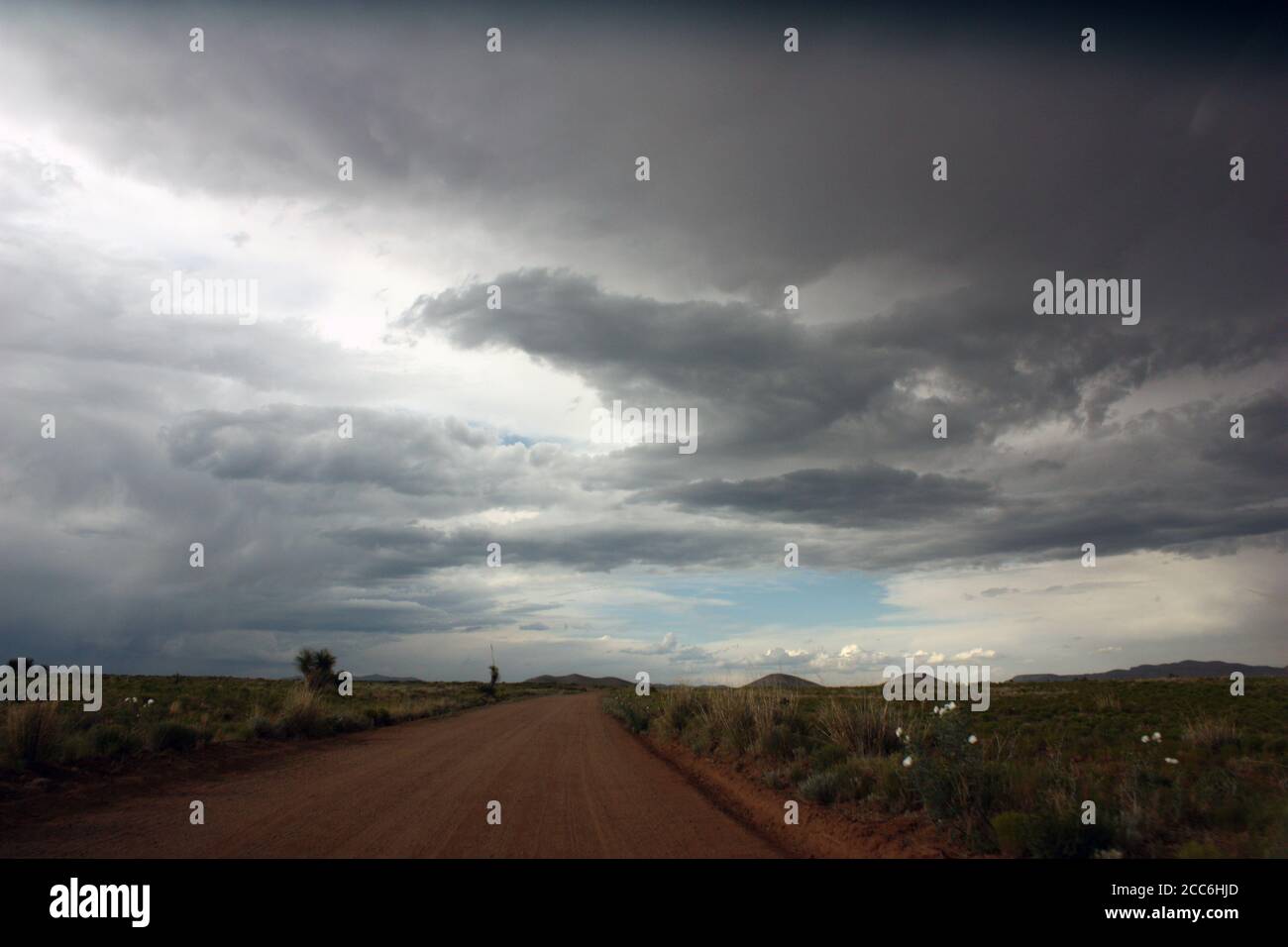 Suggestivo e selvaggio paesaggio desertico con prati aridi, montagne lontane e nuvole scure e tempestose Foto Stock