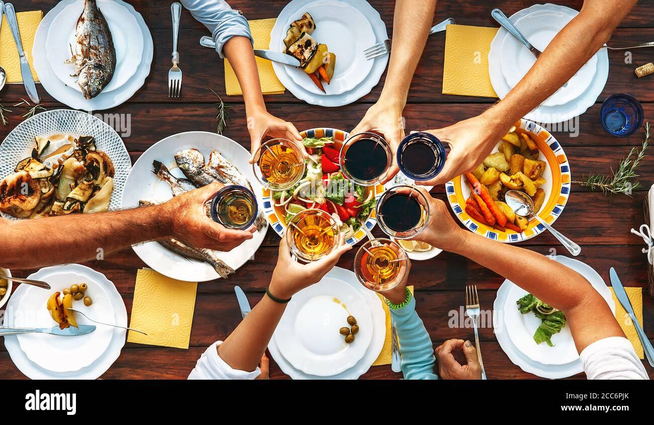 Grande cena di famiglia. Vista dall'alto sul tavolo servito e le mani con i calici di graffio Foto Stock