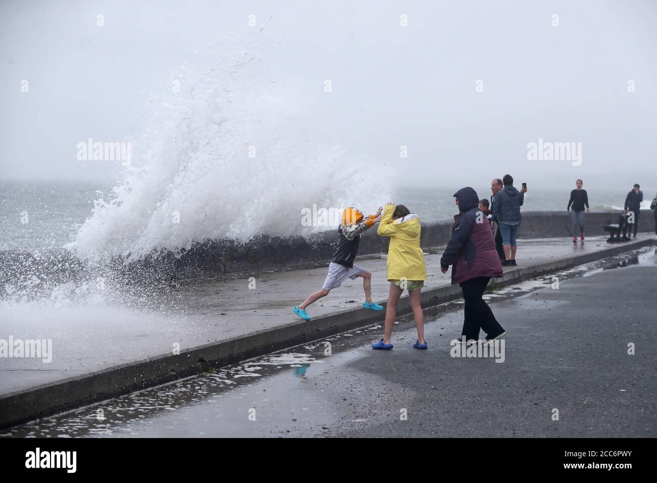 La gente è colpita dalle onde sulla parte anteriore in Youghal, Co. Cork. Met Eireann ha emesso un avviso di vento rosso per l'area e un avviso arancione è stato emesso per Galway, Mayo, Clare, Kerry, Limerick e Waterford, mentre Storm Ellen attraversa il paese da mercoledì sera. Foto Stock