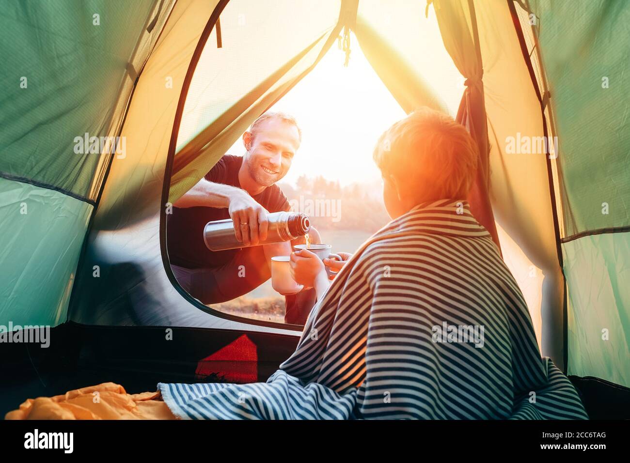 Padre e figlio bevono tè caldo in tenda turistica Foto stock - Alamy