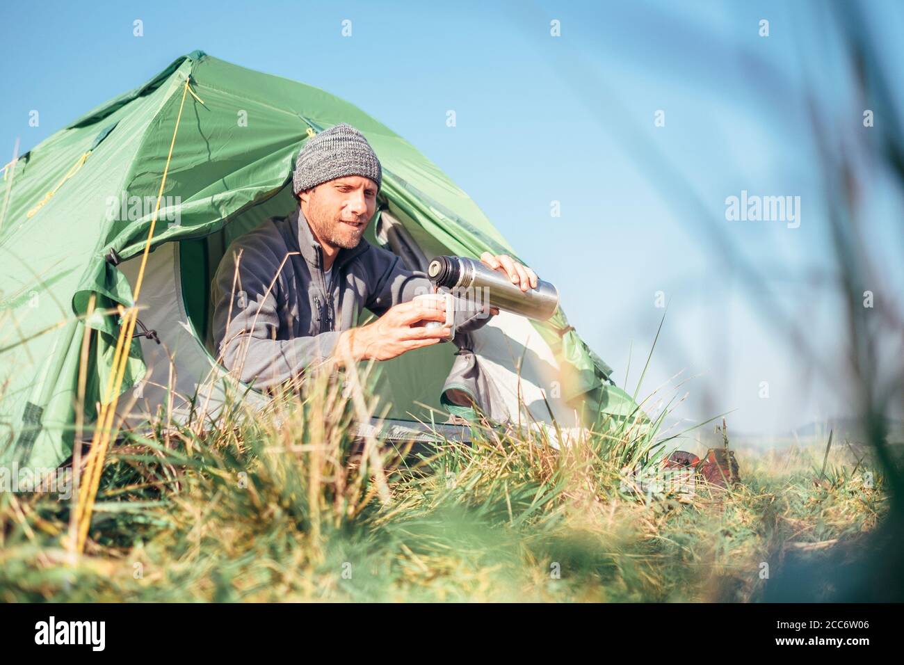 L'uomo si siede in tenda e beve il tè caldo Foto Stock