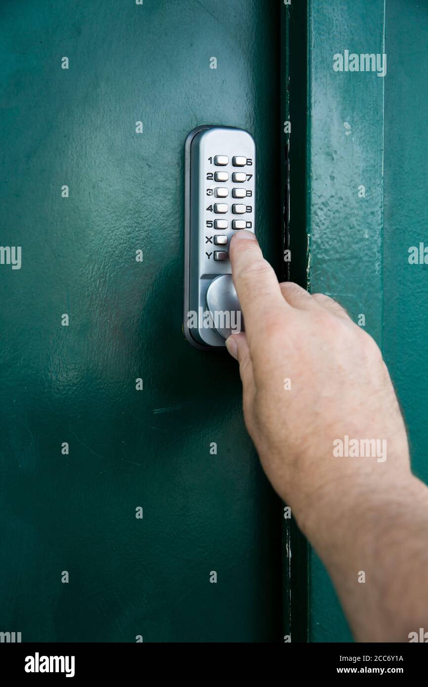 Un primo piano di una porta di sicurezza di lettere e numeri serratura a combinazione con una mano che preme un codice o. codice chiave per accedere a una posizione sicura Foto Stock