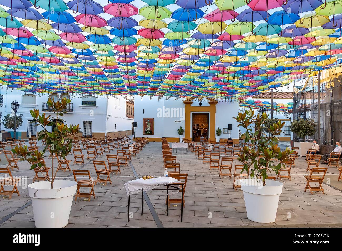 Huelva, Spagna - 15 agosto 2020; la piazza di fronte alla chiesa è preparata per una messa in strada con ombrelloni nel cielo nel villaggio di San B. Foto Stock