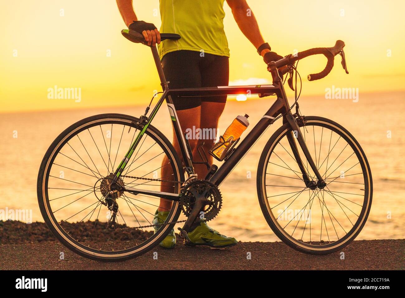 Triatleta professionista allenato con bici da strada al tramonto sull'oceano per la gara di triathlon. Atleta maschile ciclista Foto Stock