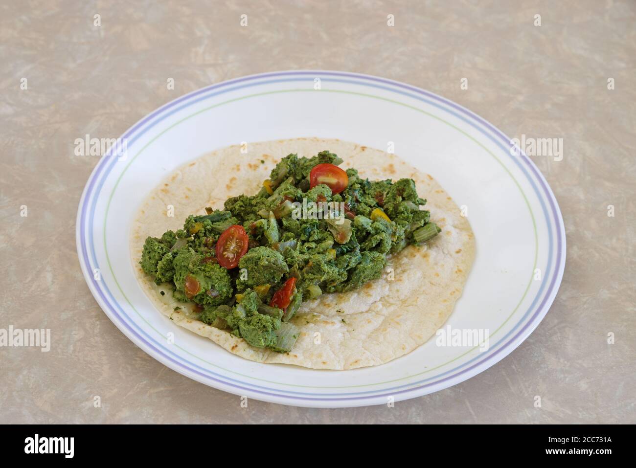 uova verdi e verdure su una tortilla di farina Foto Stock