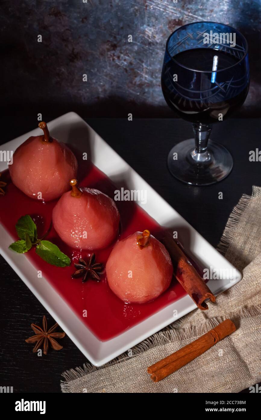 Pere in camicia in vino rosso con cannella e anice. Foto Stock