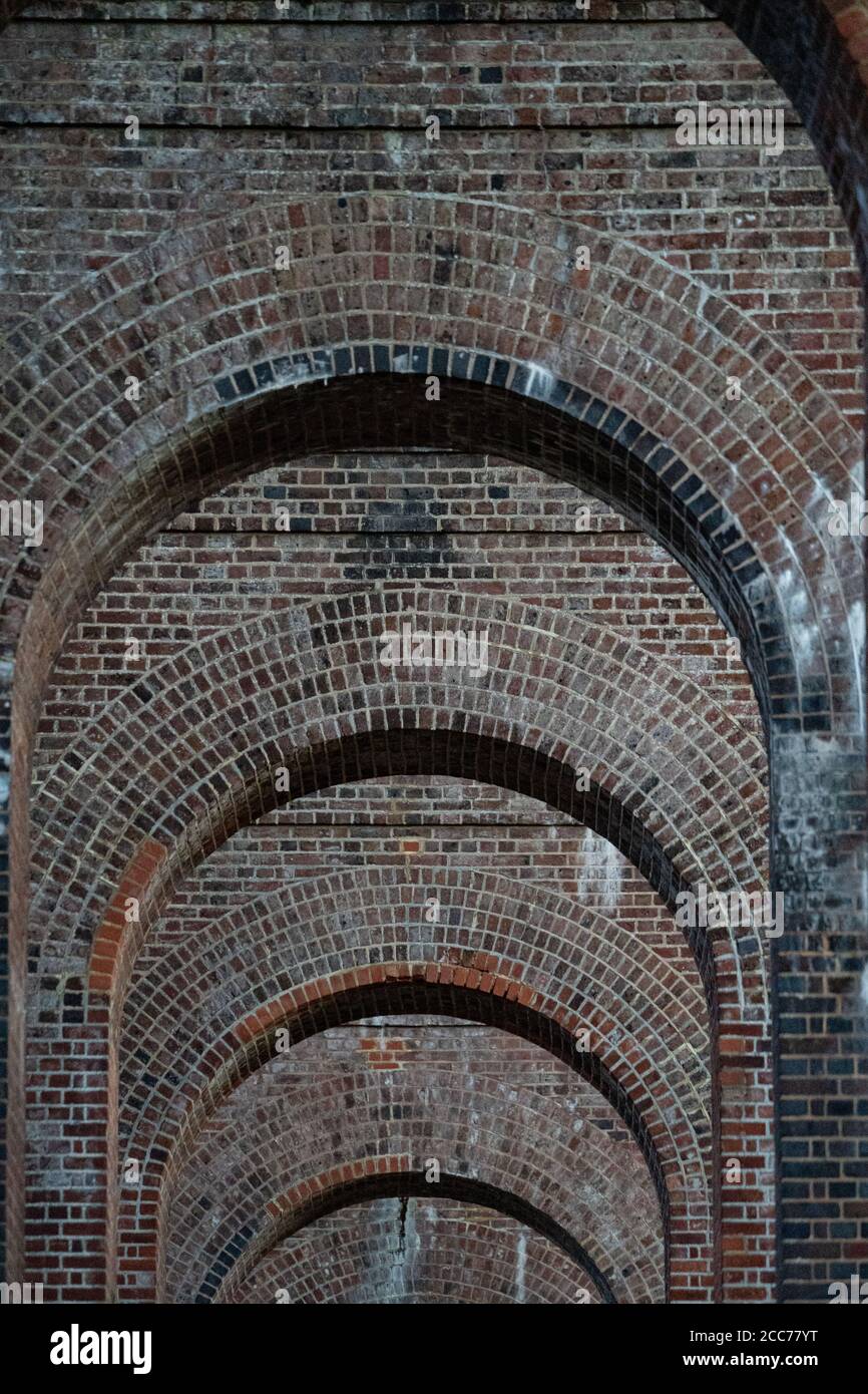 Vista attraverso gli archi del Viadotto della Valle di Ouse (Viadotto Balcombe) che porta la linea ferroviaria di Londra a Brighton sul fiume Ouse a Sussex, Regno Unito Foto Stock