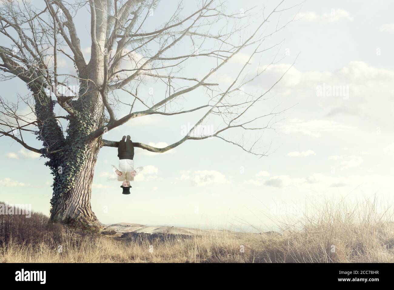 momento surreale dell'uomo che legge un libro appeso da a. diramazione a testa in giù Foto Stock