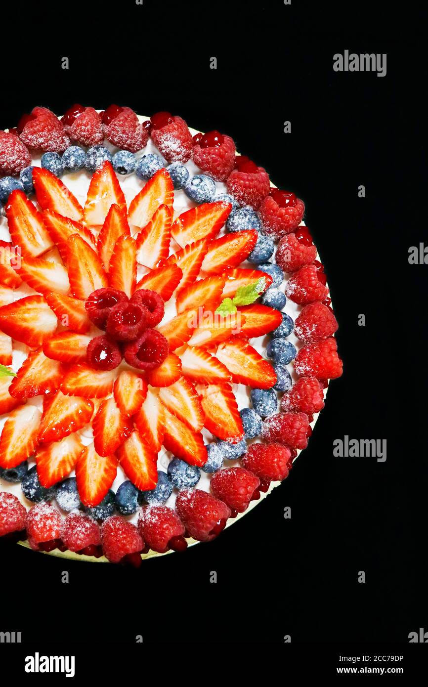 torta di frutta decorata con bacche miste assortite con sfondo nero Foto Stock