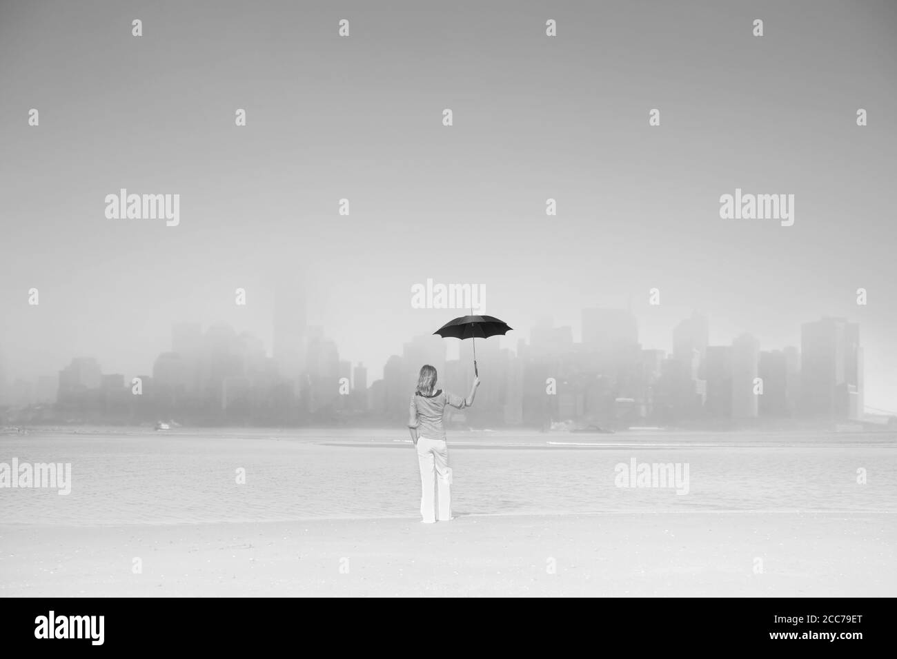 donna con ombrello nero vista grande metropoli tra la nebbia e inquinamento Foto Stock