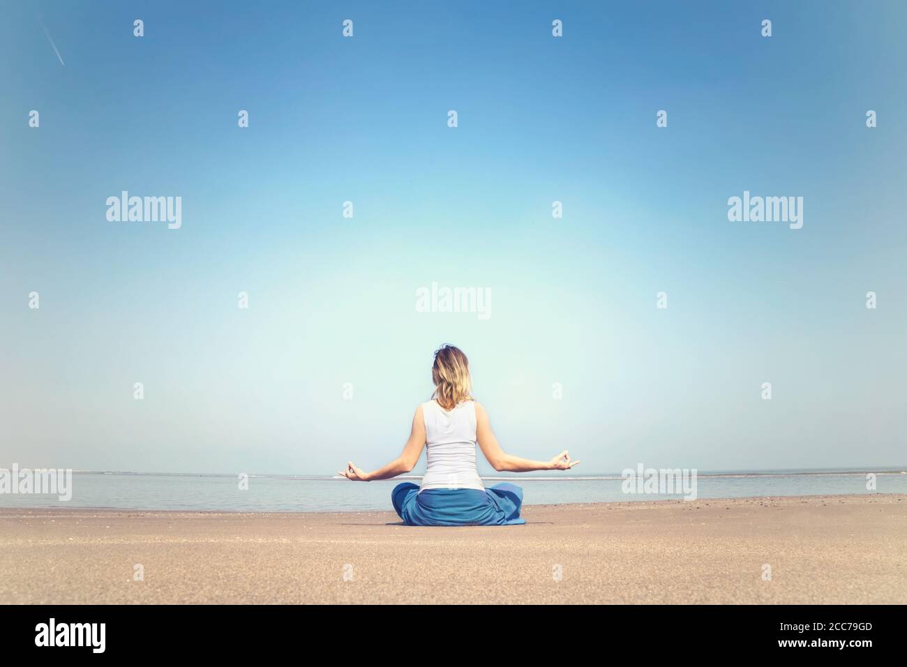 donna che esegue esercizi di rilassamento e meditazione al mare Foto Stock