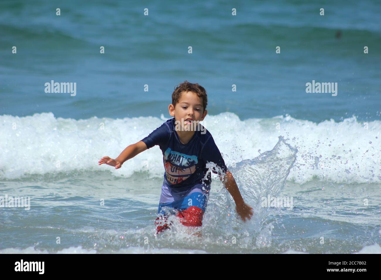 Un ragazzino (5 anni) corre e gioca nelle onde dell'oceano Foto Stock