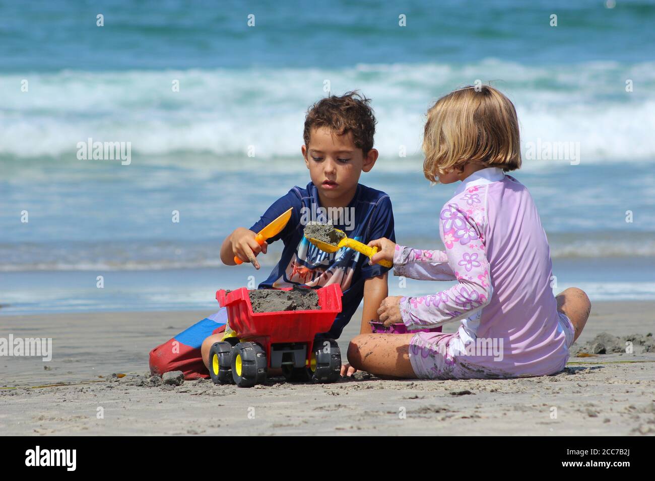 Due bambini piccoli carini (fratello e sorella) gioca insieme a giocattoli di sabbia in spiaggia Foto Stock