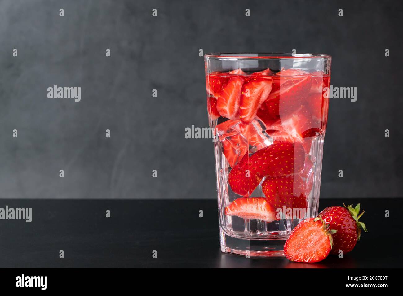 Bevanda ghiacciata con fragole su sfondo nero. Limonata di frutti di bosco estivi. Posiziona per il testo. Foto Stock