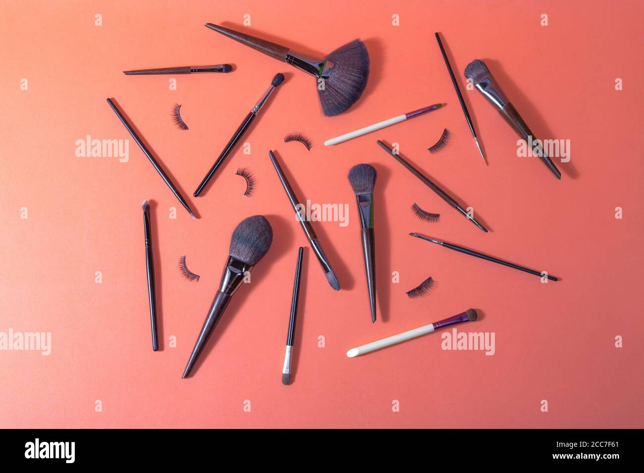 Superficie arancione su cui ci sono diversi pennelli per il trucco e. false ciglia per uso professionale Foto Stock