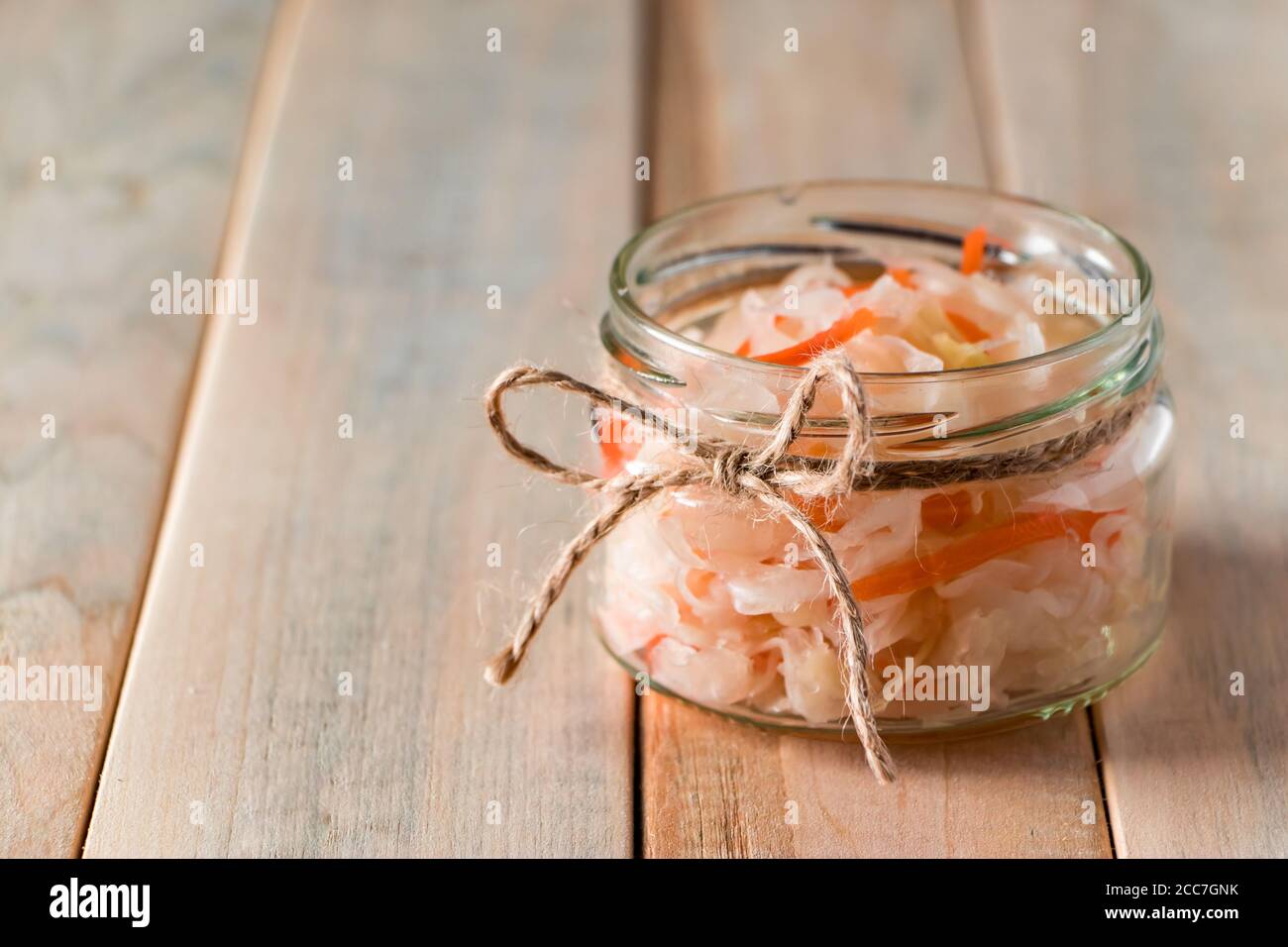 Crauti fatti in casa su uno sfondo di legno chiaro. Vasetto di vetro con cavolo fermentato fatto in casa. Cibo ecologico, la tendenza di un'alimentazione sana. Luogo per la vostra tex Foto Stock
