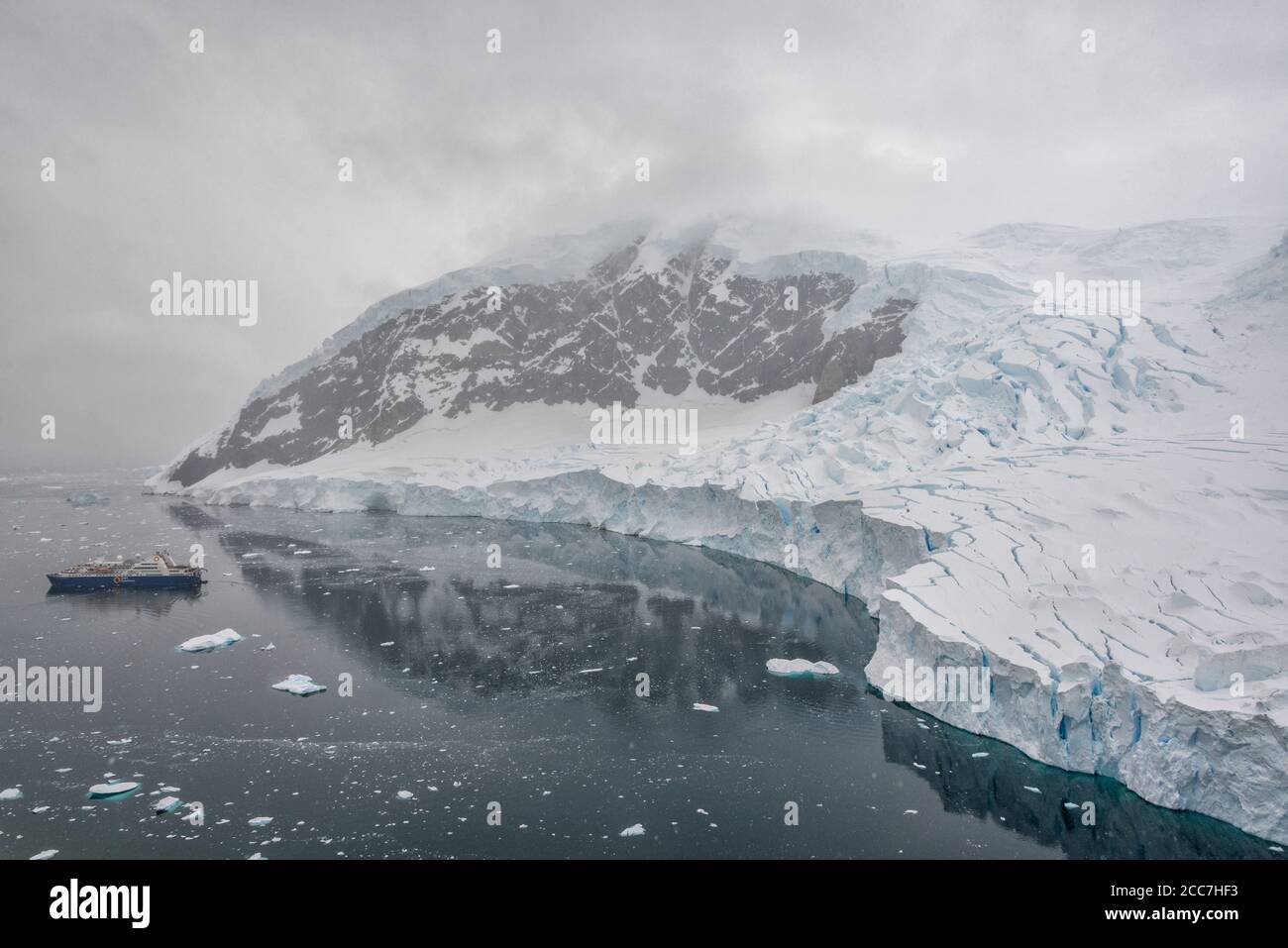 Una nave da crociera Quark Expeditions in una baia circondata da montagne ricoperte di ghiacciaio in Antartide. Foto Stock