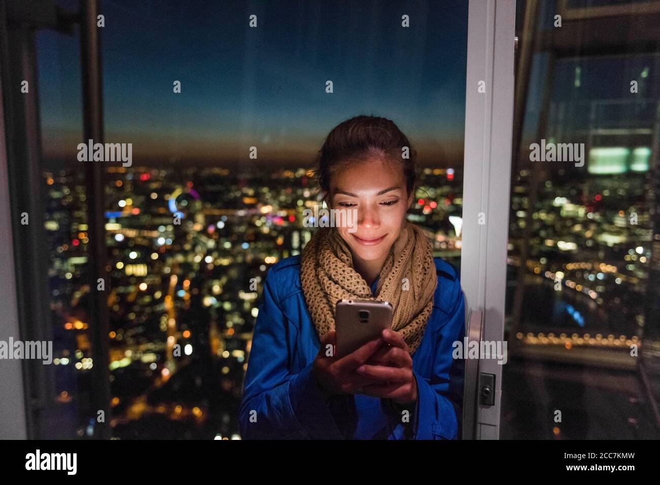 London Urban People City lifestyle donna che usa l'app per il telefono SMS sui social media. Giovane ragazza asiatica che tiene il cellulare di notte sullo skyline Foto Stock