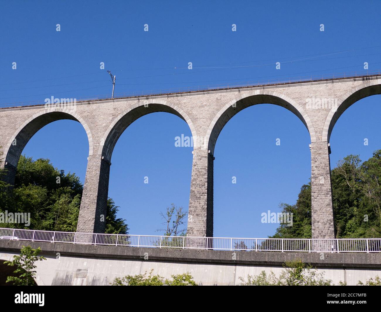 gigantesco e impressionante viadotto ferroviario senza treno di fronte al blu cielo e verde foresta con una strada e guardrail vicino giorno senza persone Foto Stock