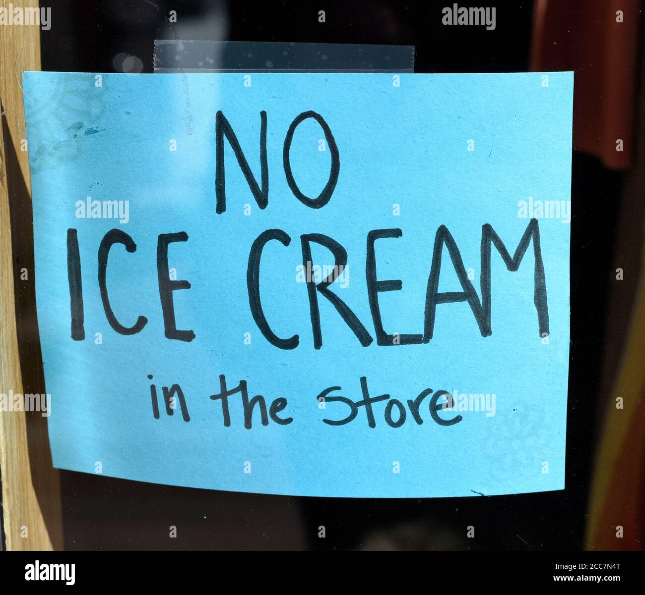 Un cartello fatto a mano apposta sulla finestra di un negozio di abbigliamento chiede ai clienti di non entrare nel negozio con il gelato acquistato presso la gelateria accanto. Foto Stock