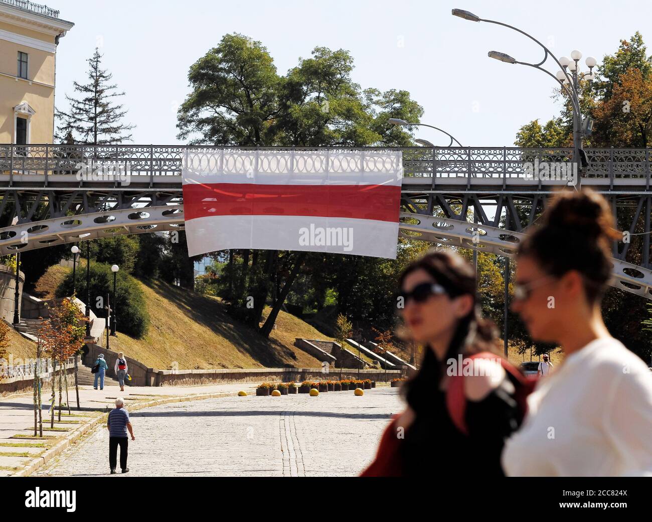Kiev, Ucraina. 19 agosto 2020. Due donne passano davanti a un'enorme bandiera storica bielorussa a sostegno delle proteste in Bielorussia è visto appeso su un ponte nella Piazza dell'Indipendenza nel centro di Kiev.le proteste dell'opposizione continuano in Bielorussia per la seconda settimana dopo le controverse elezioni presidenziali. Credit: SOPA Images Limited/Alamy Live News Foto Stock