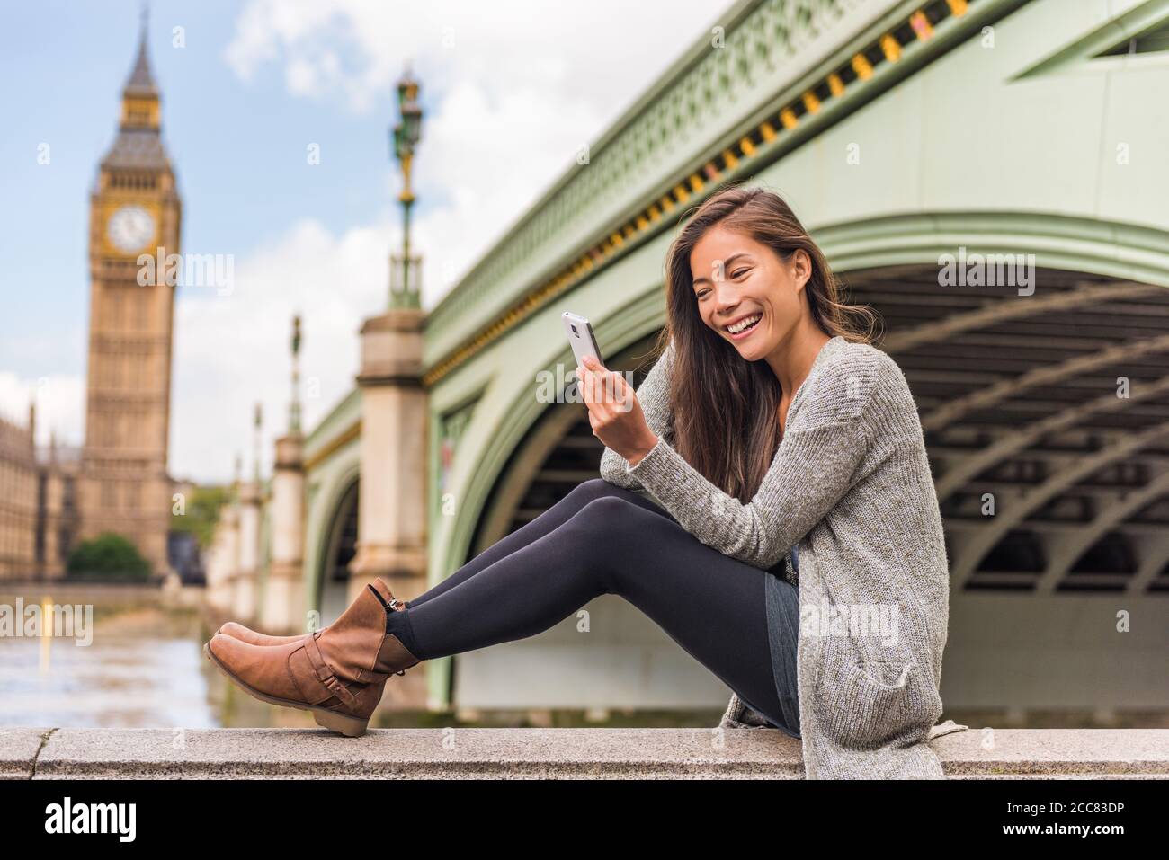 London Urban People City lifestyle donna che usa l'app per il telefono SMS sui social media. Giovane ragazza asiatica che tiene il cellulare al ponte di Westminster, Big Foto Stock