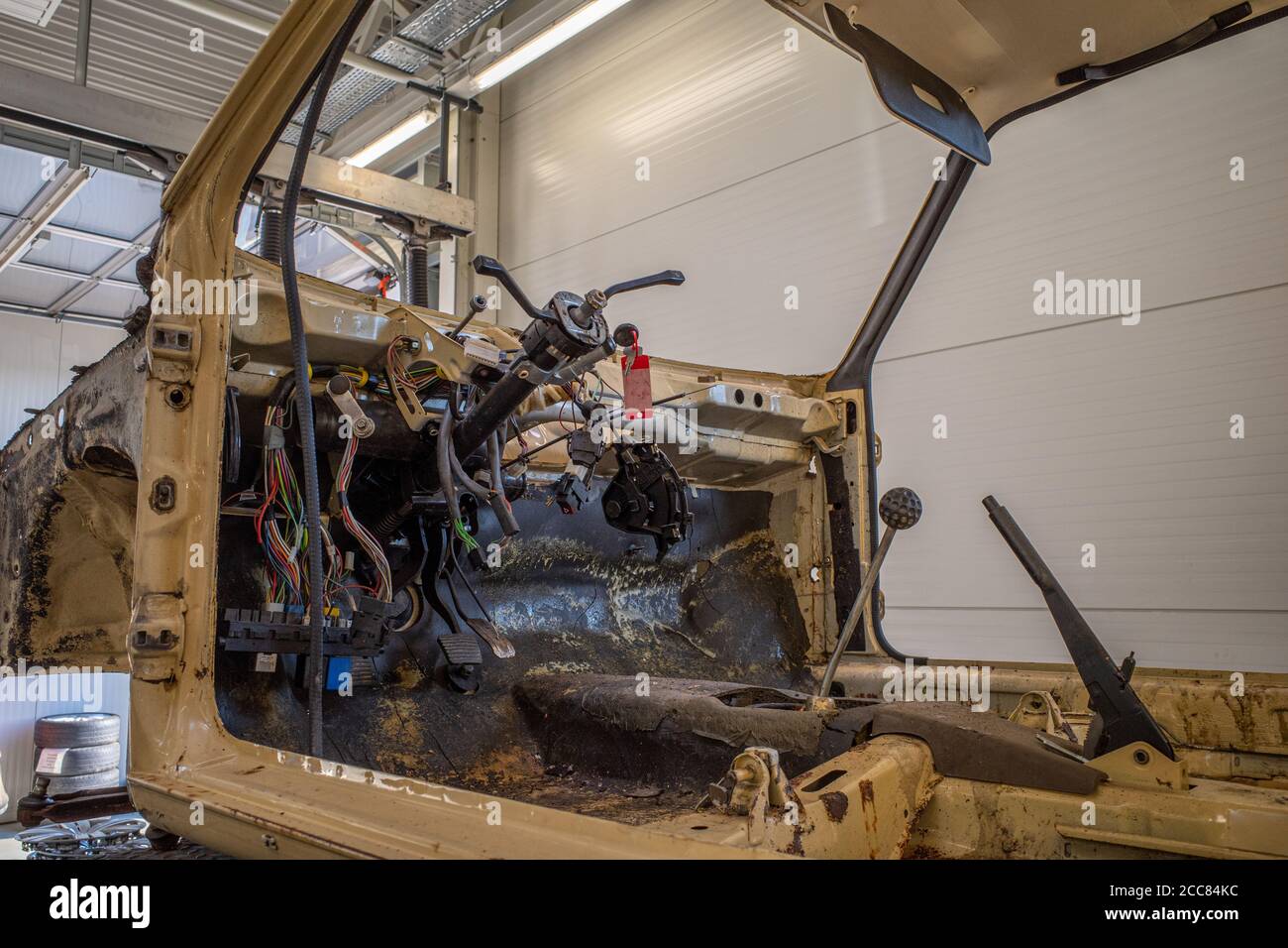 in un negozio di riparazione auto c'è un'auto spogliata senza volante Foto Stock