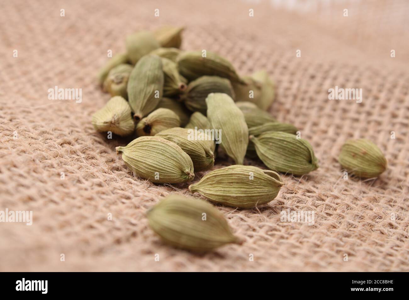cardamomo verde profumato su sfondo di iuta. Foto Stock