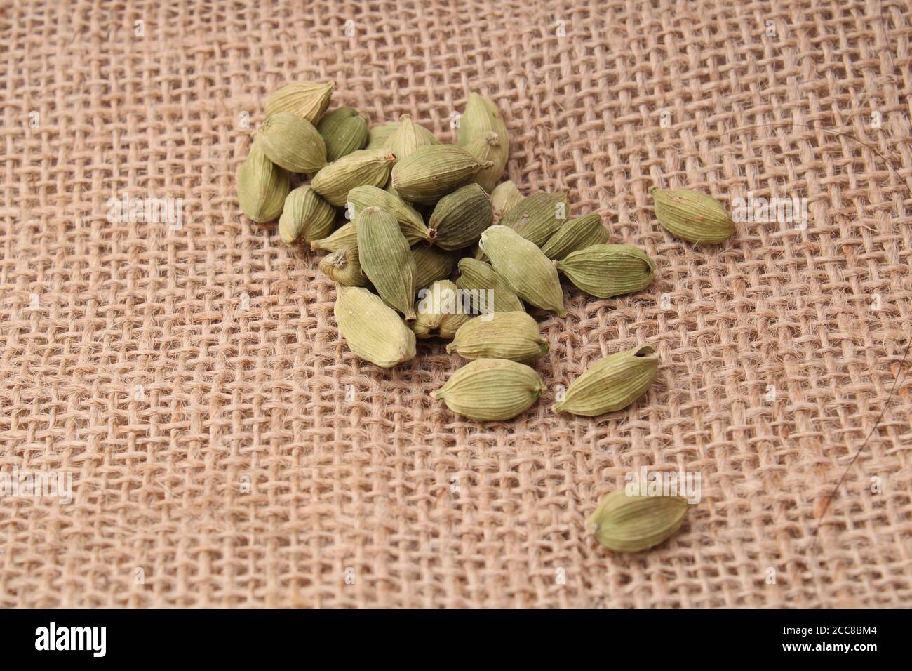 cardamomo verde profumato su sfondo di iuta. Foto Stock