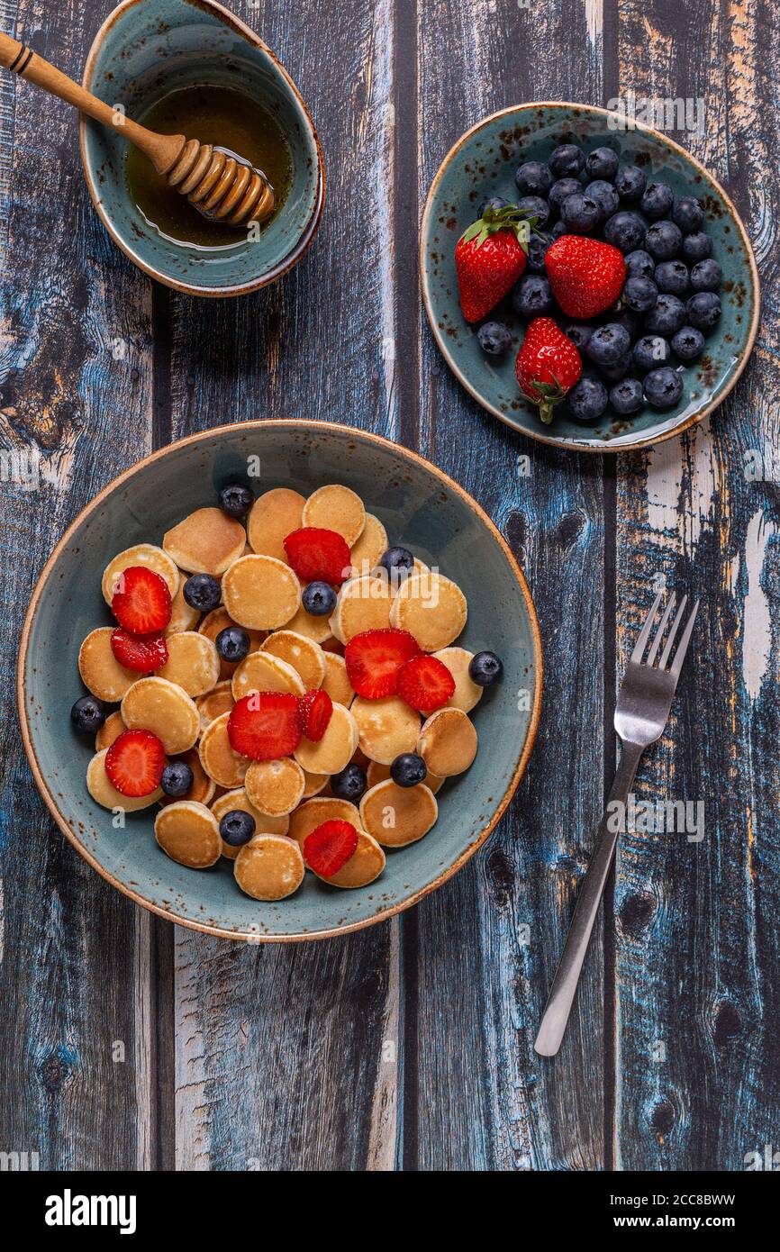 Colazione alla moda con mini pancake, mirtilli e fragole, vista dall'alto. Foto Stock