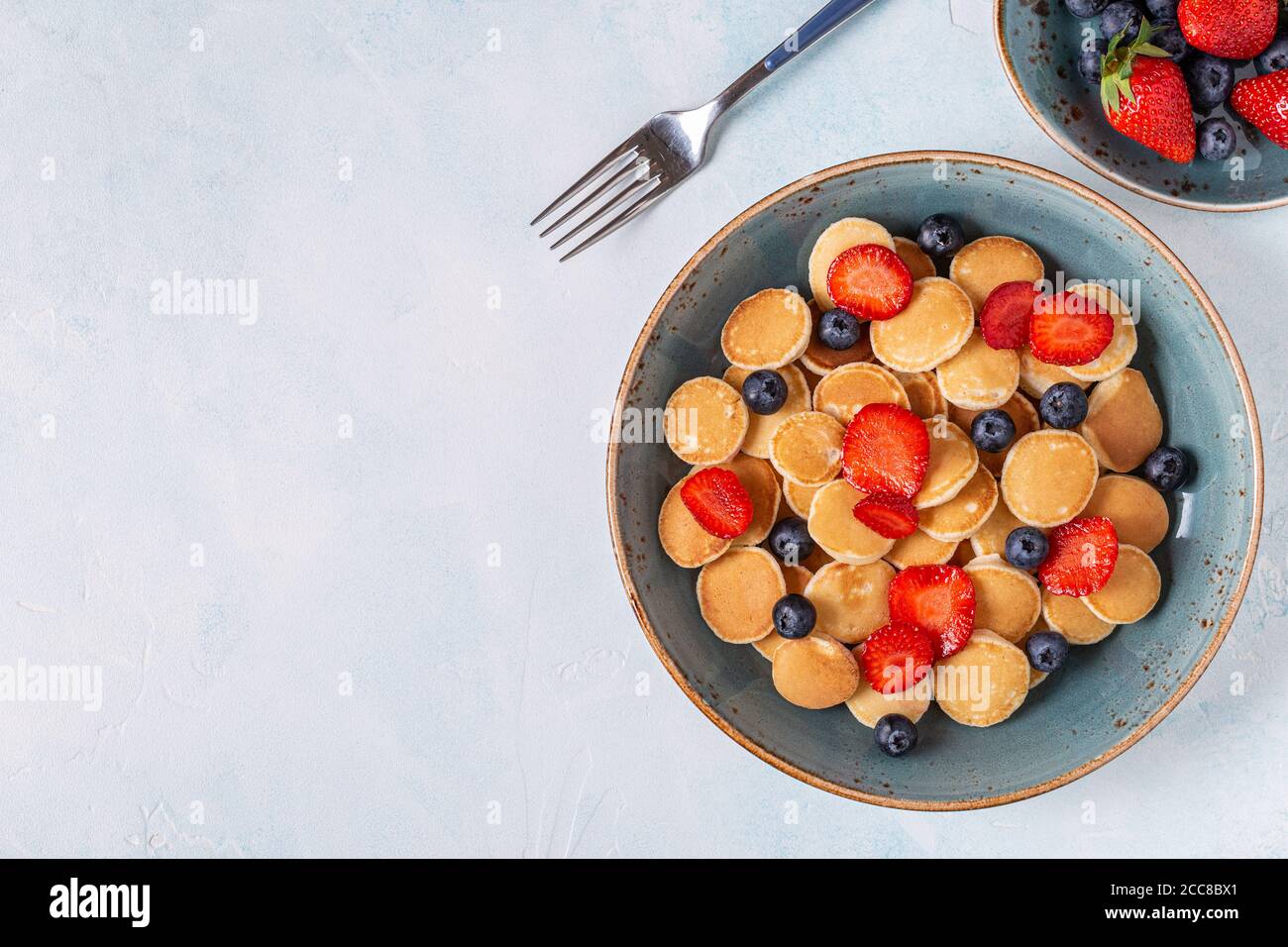 Colazione alla moda con mini pancake, mirtilli e fragole, vista dall'alto. Foto Stock