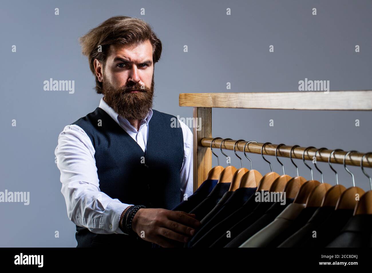 Costume da uomo, sarto nella sua officina. Abiti maschi appesi in fila. Su misura. Abito elegante da uomo. Bell'uomo di moda in stile classico Foto Stock
