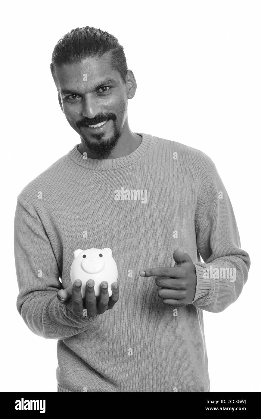 Giovani felici uomo indiano holding salvadanaio e puntare il dito Foto Stock