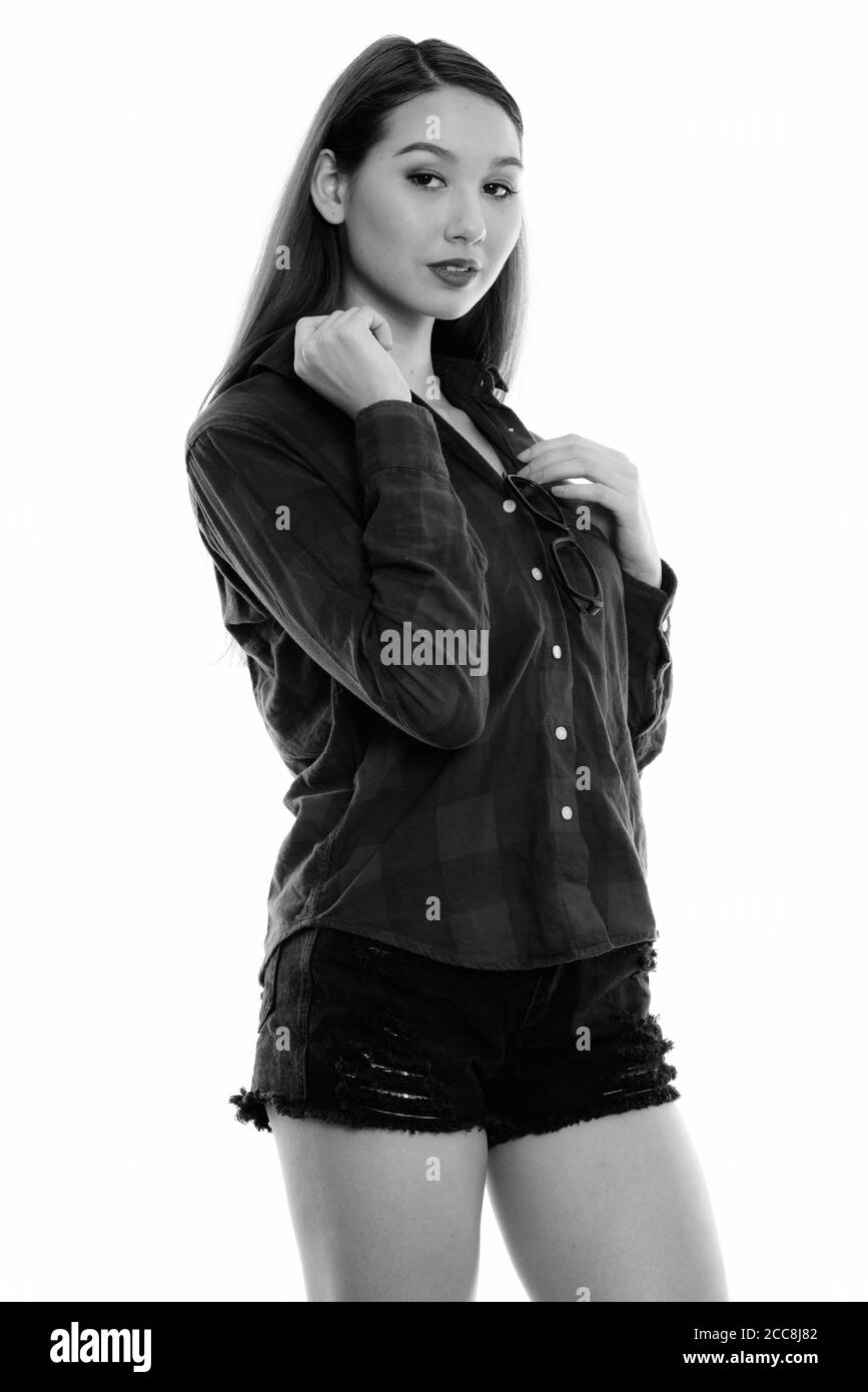Studio shot del giovane bella donna asiatica in piedi mentre la messa degli occhiali sulla camicia Foto Stock